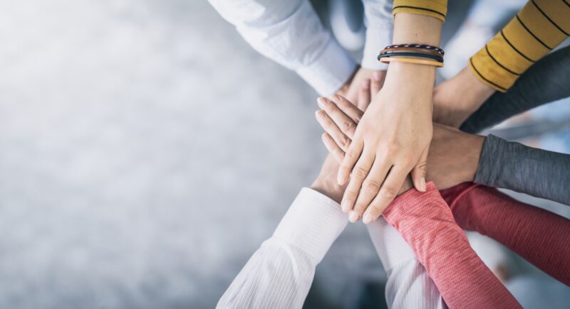 mehrere Hände übereinander gelegt, Symbol für Teamwork